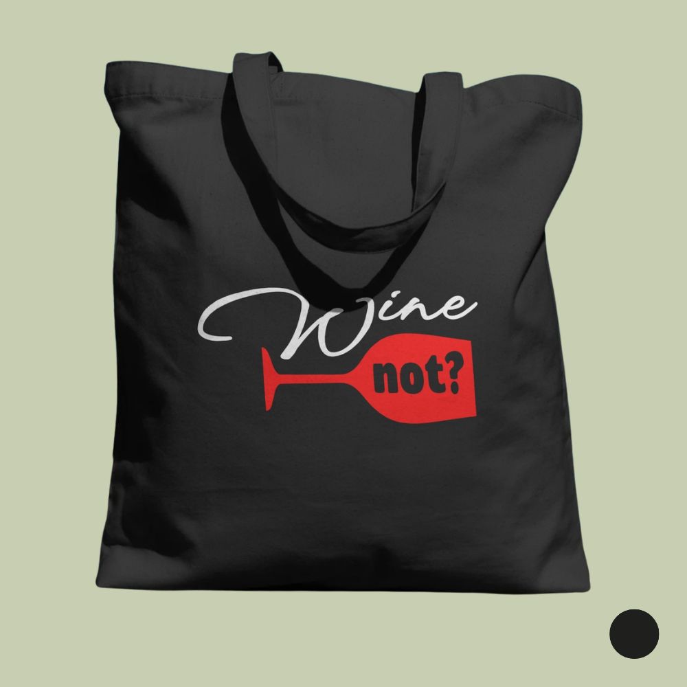 Czarna torba bawełniana, typu tote, z nadrukowaną grafiką przedstawiającą czerwony, przewrócony kieliszek do wina na dole i biały napis „Wine” powyżej. Czerwony napis „not?” jest umieszczony wewnątrz przewróconego kieliszka. Torba jest zawieszona na tle jasnej ściany ze światłami i cieniami. W prawym dolnym rogu znajduje się czarny krąg.