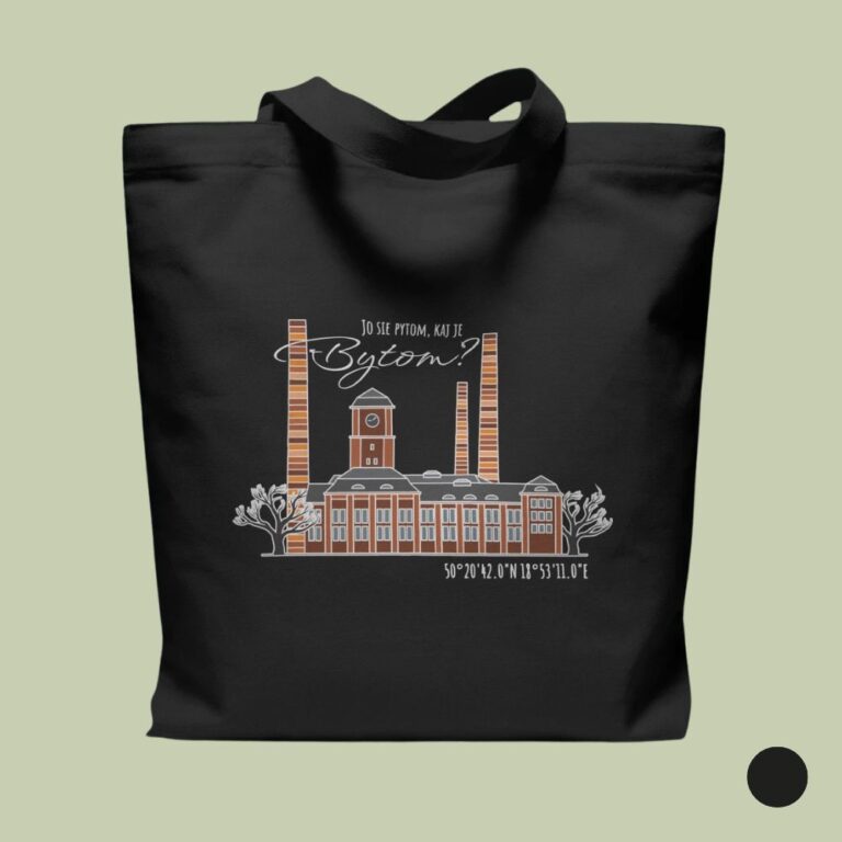 Czarna bawełniana torba na zakupy ułożona płasko na szałwiowym tle. W centrum torby znajduje się ilustracja przedstawiająca industrialny budynek z cegły z wieżą zegarową i trzonami kominowymi, ujęty między dwoma konturowymi drzewami. Nad budynkiem umieszczono biały napis „JO SIE PYTOM, KAJ JE Bytom?”, a poniżej współrzędne geograficzne „50°20'42.0"N 18°53'11.0"E”. W prawym dolnym rogu widoczny jest czarny okrąg oznaczający opcję kolorystyczną.