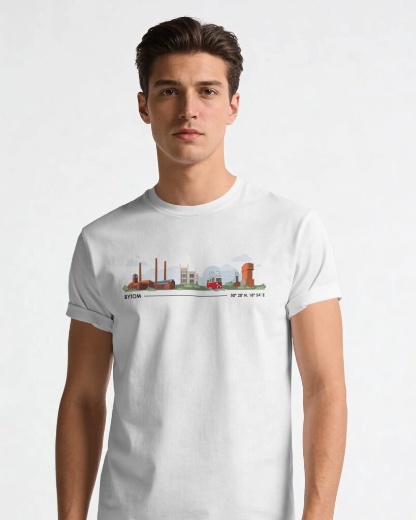 Młody mężczyzna stojący na jasnym, neutralnym tle, ubrany w białą koszulkę T-shirt z krótkim rękawem. W centralnej części koszulki umieszczono kolorowy nadruk przedstawiający zabytkowe i przemysłowe obiekty Bytomia, w tym czerwono-żółty tramwaj oraz szyby górnicze. Pod grafiką widnieje napis „BYTOM” wraz ze współrzędnymi geograficznymi miasta.