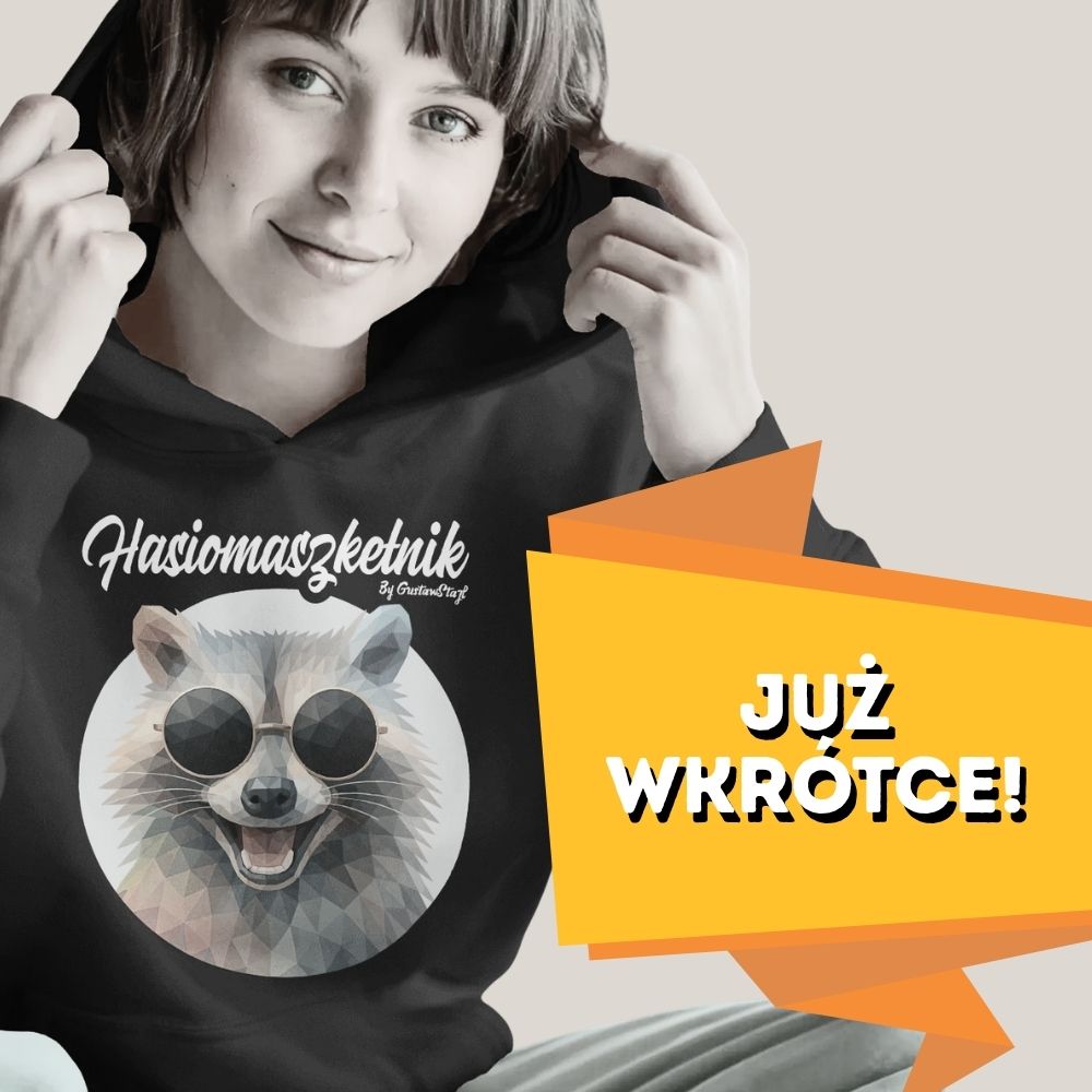 Młoda uśmiechnięta kobieta w czarnej bluzie z kapturem, z rękami podtrzymującymi brzegi kaptura. Na przodzie bluzy nadrukowana jest okrągła ilustracja z głową szopa pracza w ciemnych okularach i napisem „Hasiomaszketnik”. Po prawej stronie w dole widnieje duża, pomarańczowa bannerowa wstęga z białym napisem „JUŻ WKRÓTCE!”.