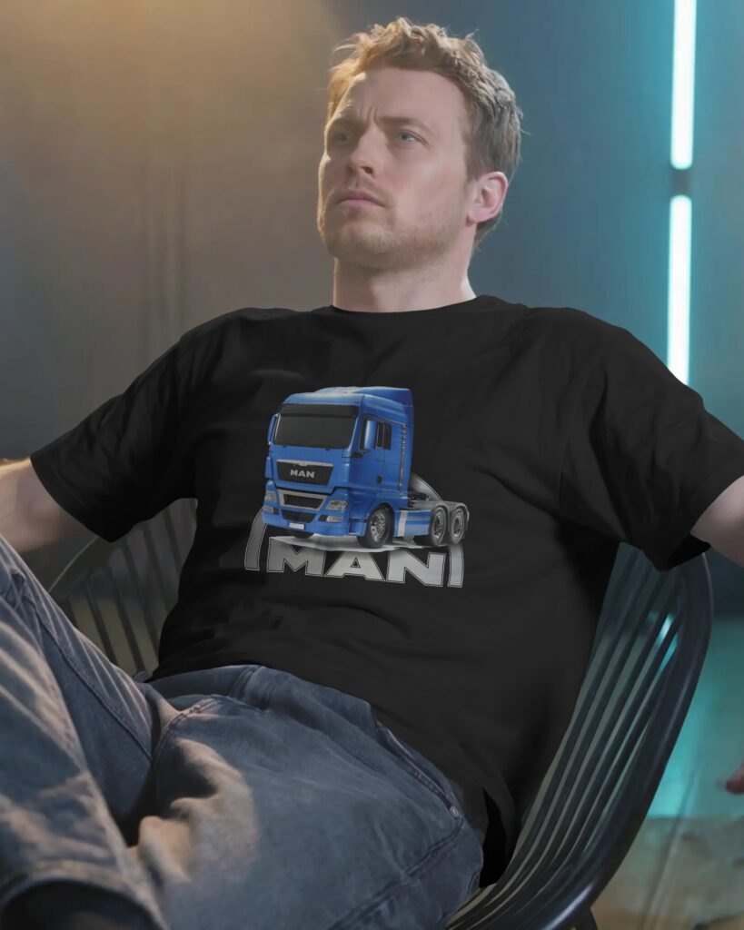 Mężczyzna o krótkich blond włosach siedzi odprężony w nowoczesnym, ażurowym fotelu. Ma na sobie czarny T-shirt z nadrukiem przedstawiającym niebieski ciągnik siodłowy z dużym napisem „MAN” poniżej, oraz niebieskie dżinsy. Kadru dopełnia ciemne studio z delikatnym, turkusowym podświetleniem z tyłu.