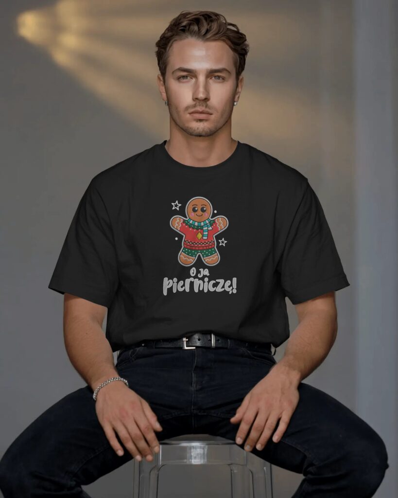Mężczyzna o krótkich, brązowych włosach siedzący na przezroczystym stołku z dłońmi opartymi na udach. Ubrany jest w czarny T-shirt oraz ciemne spodnie ze skórzanym paskiem. Na środku koszulki znajduje się nadruk przedstawiający uśmiechniętego piernikowego ludzika w czerwono-zielonym swetrze i szaliku, a pod nim biały napis „O ja Pierniczę!”.